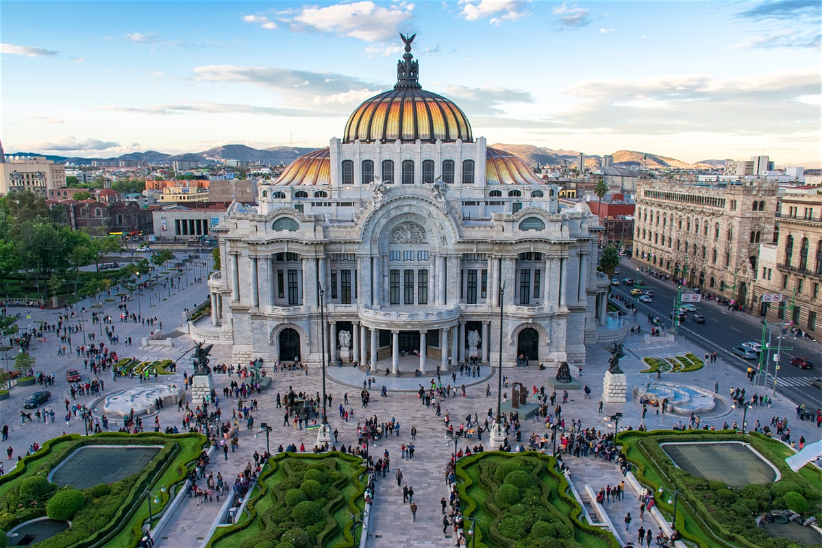 mexico city mexico with the palacio de bellas artes gardens and many people under a blue sky