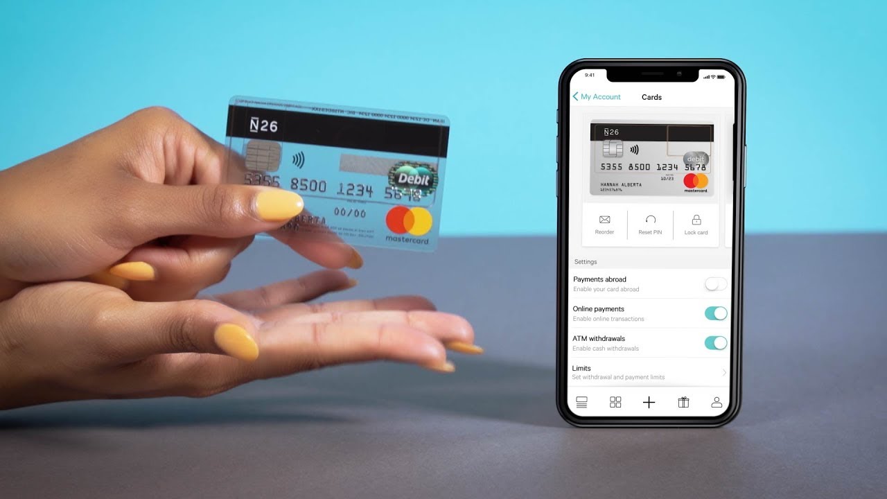 N26 bank card held in the hand of a woman who is comparing it to a mobile phone