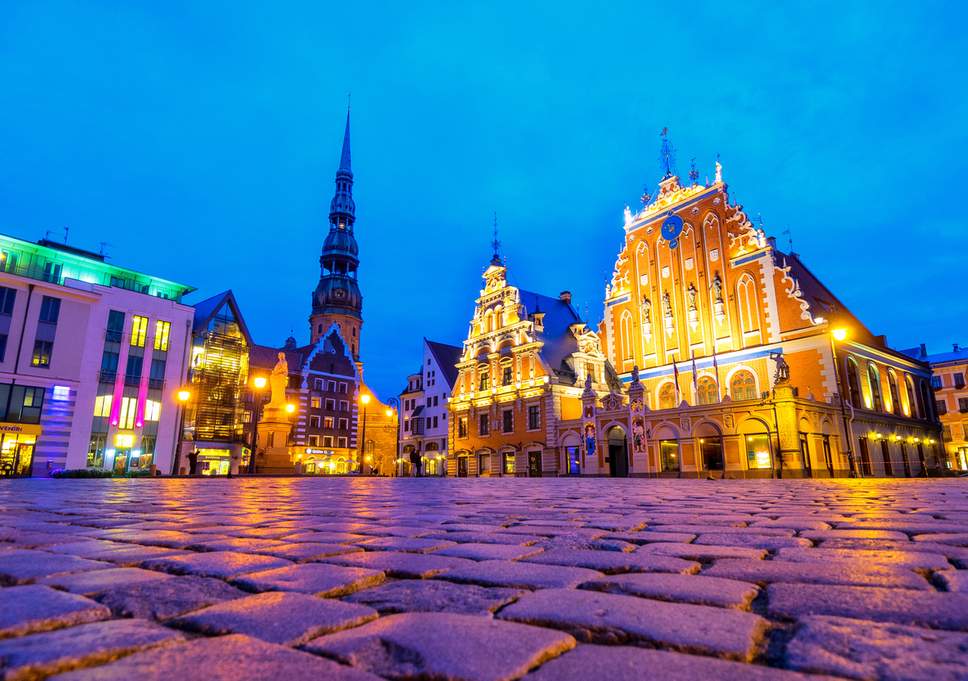 riga latvia church and town hall town square lit with purple and orange light