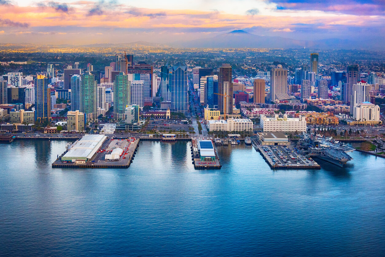 view of san diego with pacific ocean piers buildings skyscrapers a mountain and beautiful orange pink cloudy sky