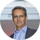 older man, light blue shirt, dark grey suit, glasses, slightly smiling