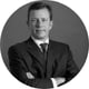 photo, man standing, holding hands, black suite, dark tie, white shirt, black and white picture, smiling, brown hair