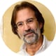 man, grey beard, brown hair, white shirt, glasses, background of a beige wall