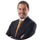 man smiling, white shirt, orange tie, black suit, short brown hair, moustache