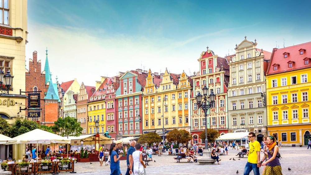 wroclaw poland colouful buildings town square tourist people church sky cafes restaurants