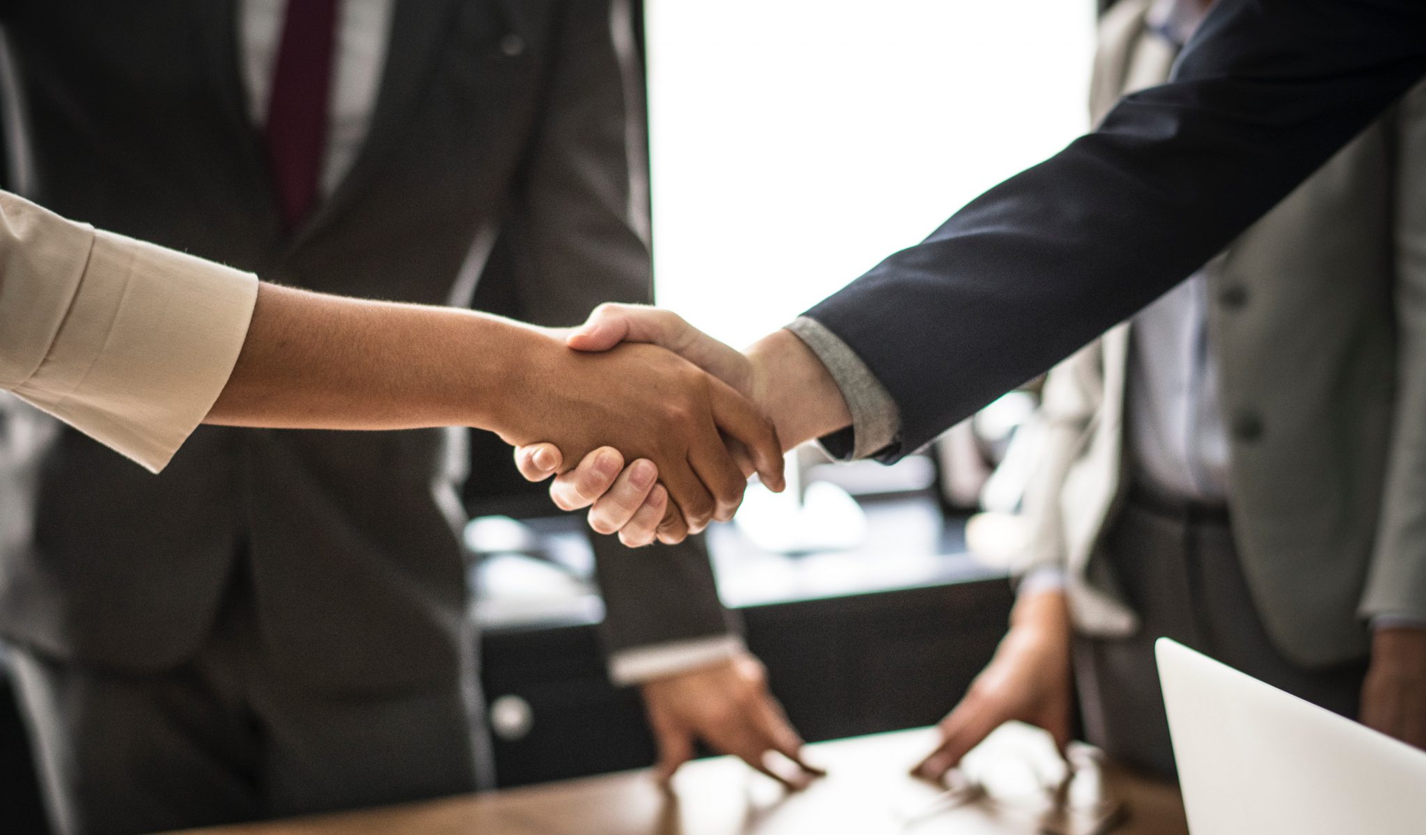 Two people shaking hands with two people in the background