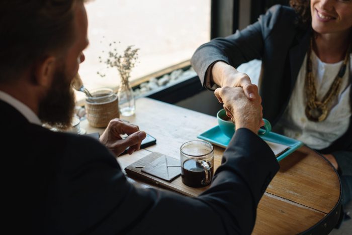 Agreement, two people shaking hands over table