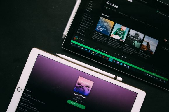 graphic of an ipad and another tablet, the screens both show spotify playing