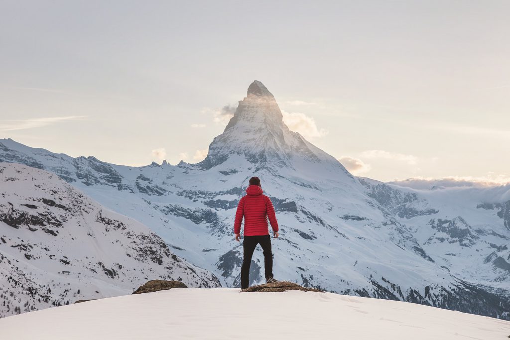 Man stands on a top of a mountain in snow