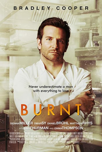 Burnt movie poster - a man wearing a chefs uniform stands in a kitchen, white black and orange lettering overlaid