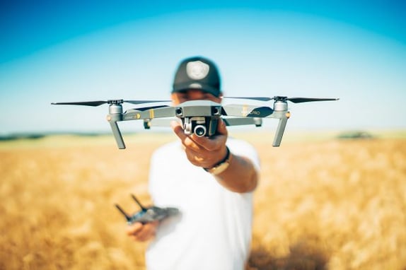 A man holding up a drone in the field