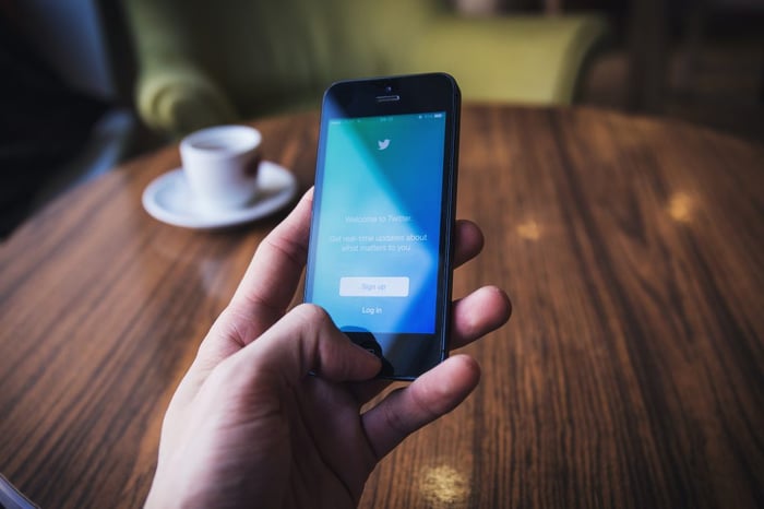 person holding a phone with twitter on the screen